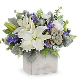 White lilies and purple flowers arranged in a square box