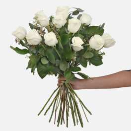 Bouquet of white roses with greenery held in a hand