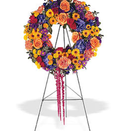 Vibrant multicolor wreath of roses, carnations, and daisies displayed on a standing easel