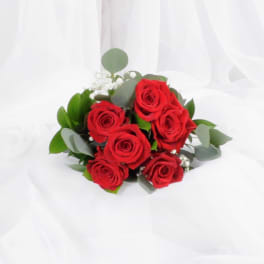 Hand-tied bouquet of red roses with white filler flowers on white fabric