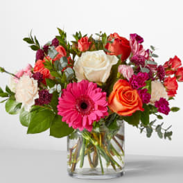 Mixed bouquet of roses, gerbera daisy, and carnations in a glass vase