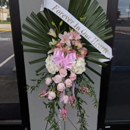 Standing floral spray with pink and white flowers and a memorial ribbon