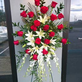 Tall standing arrangement of red roses and white lilies on an easel