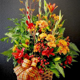 Autumn flower basket with orange lilies, yellow mums, and a plaid bow