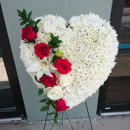 Heart-shaped floral spray with white blooms and red roses on a stand