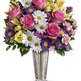 Mixed bouquet of pink roses, white daisies, and purple flowers in a silver vase