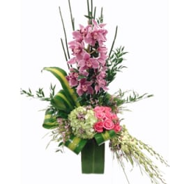 Tall floral arrangement with pink orchids and roses in a green vase