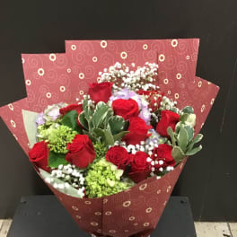 Bouquet of red roses with white filler flowers in patterned wrapping