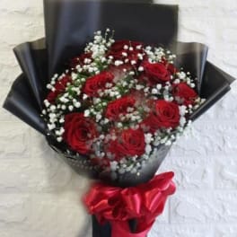 Bouquet of red roses with white baby's breath wrapped in black paper