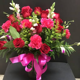 Red roses and pink carnations in a vase with a pink ribbon