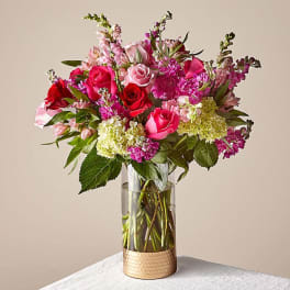 Pink and red roses with mixed blooms in a clear glass vase