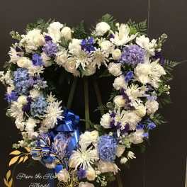 Heart-shaped white and blue floral wreath on an easel with a blue ribbon
