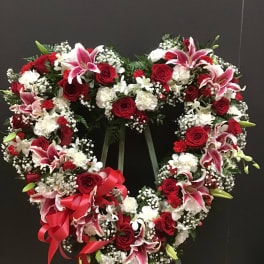 Heart-shaped floral wreath with red roses, pink lilies, and white flowers