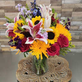Mixed bouquet with lilies, sunflowers, and roses in a glass vase