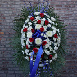Standing funeral spray of red and white flowers with blue ribbon