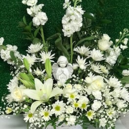 White floral basket with lilies, daisies, and an angel figurine