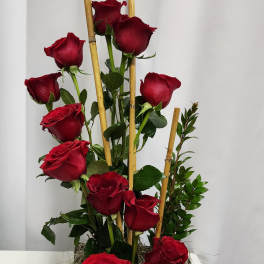 Tall arrangement of red roses in a black tray with bamboo stakes