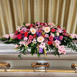 Pink and red floral casket spray on a silver casket