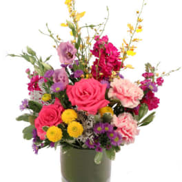 Mixed bouquet of pink, purple, and yellow flowers in a glass vase