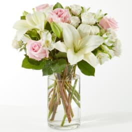 Pink roses and white lilies arranged in a clear glass vase