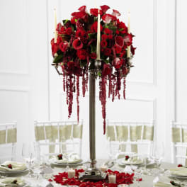 Tall silver candelabra centerpiece with red roses and candles on a formal round table.