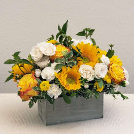 Yellow sunflowers and white roses in a gray wooden box