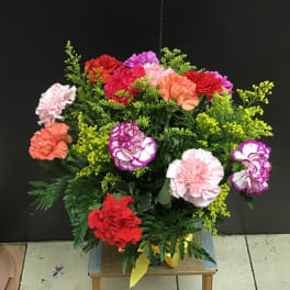 Mixed carnations in bright colors with yellow filler in a vase
