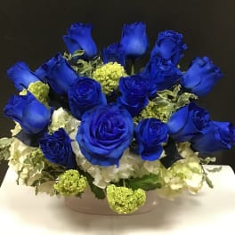 Blue roses and white hydrangeas arranged in a low white container