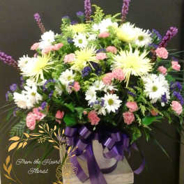 Large mixed flower arrangement with purple ribbon on a pedestal