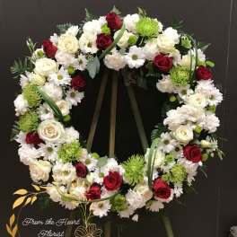 Circular funeral wreath of red and white flowers on a stand