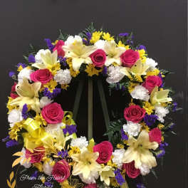 Heart-shaped floral wreath with pink roses, lilies, and yellow daisies