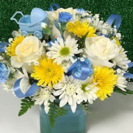 Blue and white flower arrangement in a square vase with a baby carriage decoration