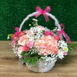 White basket of pink and white flowers with baby’s breath and pink bows on the handle