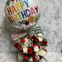 Red and white flower arrangement with a Happy Birthday balloon in a gray container
