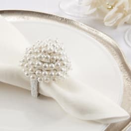 White napkin with a pearl napkin ring on a gold-rimmed plate