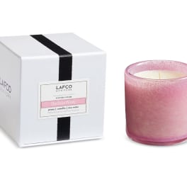 Pink scented candle in a glass holder beside its white box