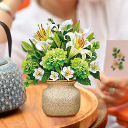 Arrangement of white lilies and green hydrangeas in a ceramic vase