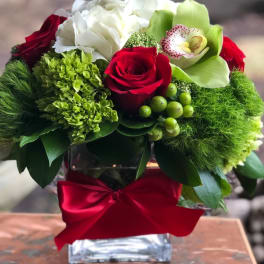 Red roses and white blooms in a glass vase with a red ribbon