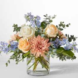 Mixed bouquet of roses, chrysanthemum, and blue flowers in a glass vase