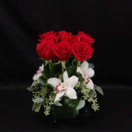 Red roses and white orchids arranged in a glass vase