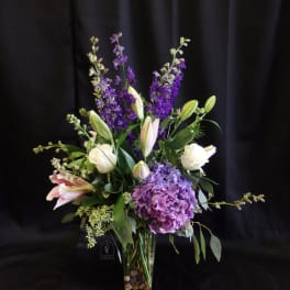 Purple and white floral arrangement in a clear glass vase