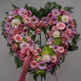Heart-shaped floral wreath with pink and white flowers and a pink ribbon