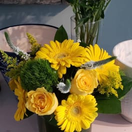 Compact yellow gerbera daisy and rose arrangement in a short glass vase