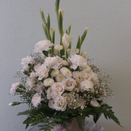 White floral arrangement in a woven basket with tall green stems