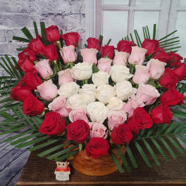 Heart-shaped bouquet of red, pink, and white roses in a basket