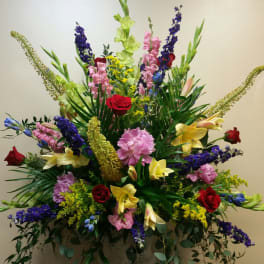 Large mixed floral arrangement in a pedestal vase with roses and lilies