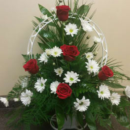 Red roses and white daisies arranged in a white standing frame