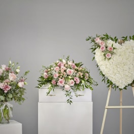 Sympathy set with pink and white arrangements and a white heart wreath on a stand