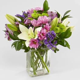 Mixed bouquet of pink and purple flowers in a clear glass vase