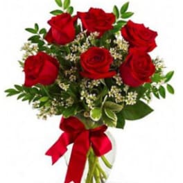 Bouquet of red roses with greenery and a red ribbon in a glass vase